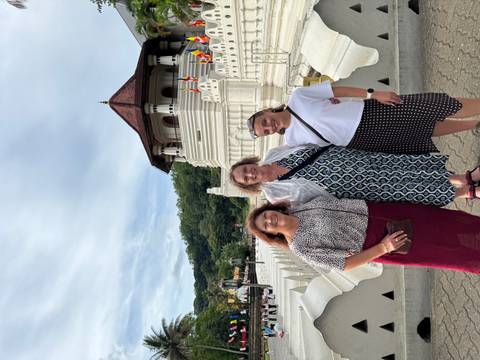Three women posing in front of the Temple of the Tooth’s white stupa and moat in Kandy