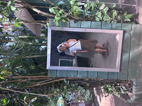 Mirror selfie of two women in a tropical garden with palm fronds and brick wall