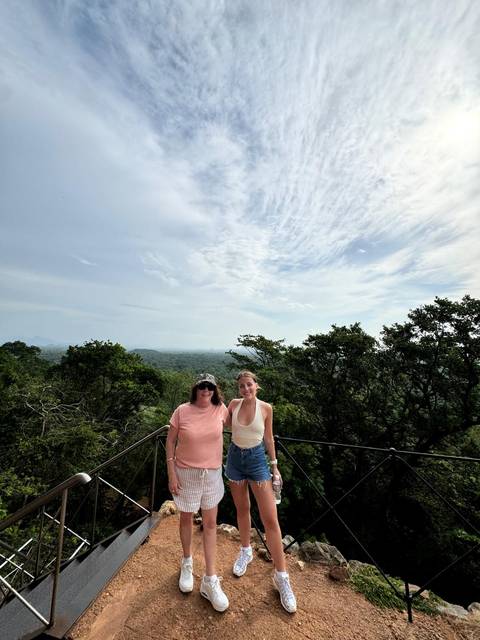 Two women on a lookout platform above dense green jungle stretching to the horizon