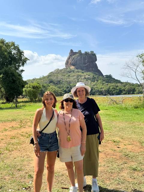 Three travelers posing with Sigiriya Rock Fortress towering in the background