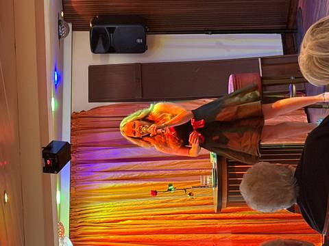 Female singer performs on stage aboard a river cruise ship lounge lit by colorful spotlights