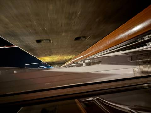 Night view from ship passing tightly through a lock chamber with concrete walls and metal railing in foreground