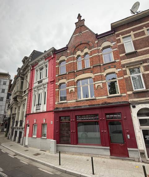Row of ornate brick and stone townhouses with varied facades under grey skies