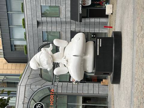 Large white Smurf statue perched on a mushroom outside Brussels Comic Strip Center