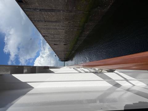 Side view from a river cruise ship entering a high-walled lock chamber under a mix of sun and clouds.