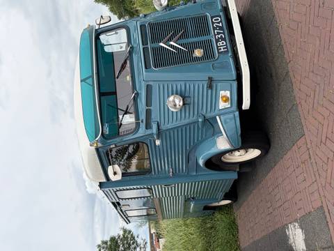 Retro blue Citroën food truck parked on a brick roadside with cloudy skies overhead.