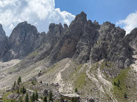 Steep jagged ridgeline of craggy limestone peaks and green gullies beneath scattered clouds.