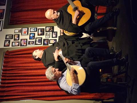 Evening live Fado performance with two guitarists and a vocalist on a small stage