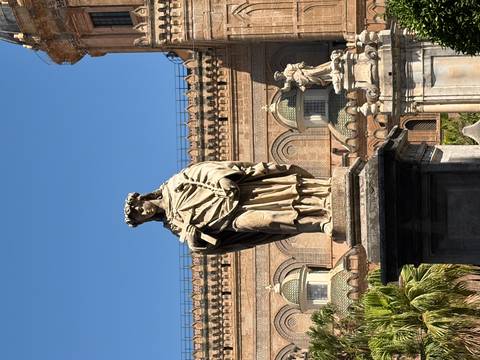 Stone statue in front of the ornate facade of Palermo Cathedral