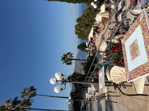Sunny terrace with decorative tiled tables, palm trees and sea view in Taormina
