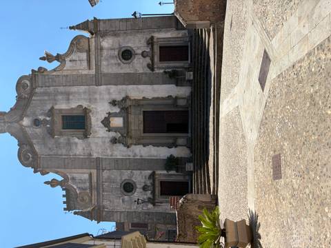 Weathered stone church facade with arched doorway in a quiet Sicilian hill town