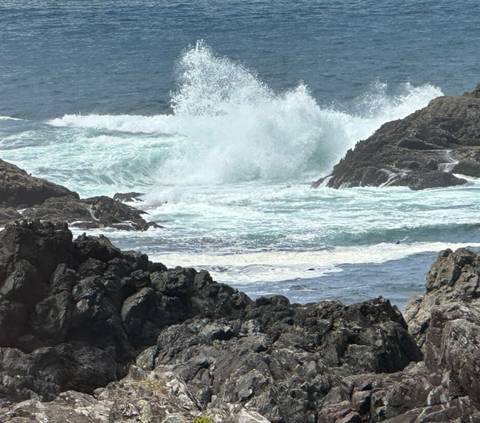 Powerful ocean waves crash against dark volcanic rocks on rugged shoreline