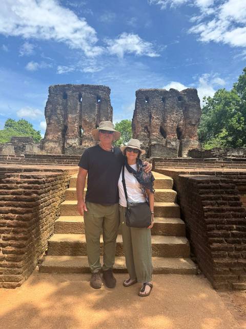 Travelling couple stands in front of ancient brick ruins with towering walls