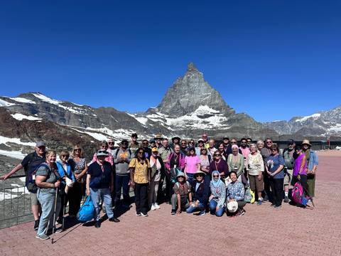 Large tour group posing on a plateau with the snow-capped Matterhorn towering behind.