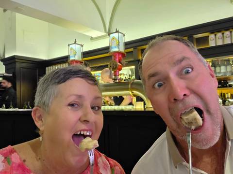 Couple playfully eating dumplings in a traditional restaurant interior.