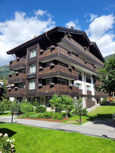 Charming alpine apartment building with carved wooden balconies and flower boxes.