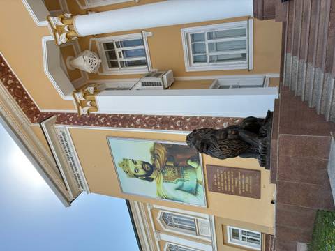 Government building façade with a large portrait of a king and bronze lion statue in Tajikistan.