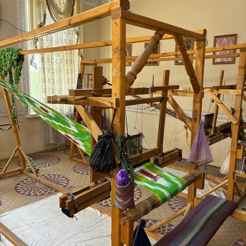 Traditional silk weaving workshop with wooden looms, colourful threads and tools.