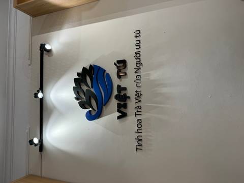 Wall logo and Vietnamese text for 'Việt Tú' tea brand under spotlights.