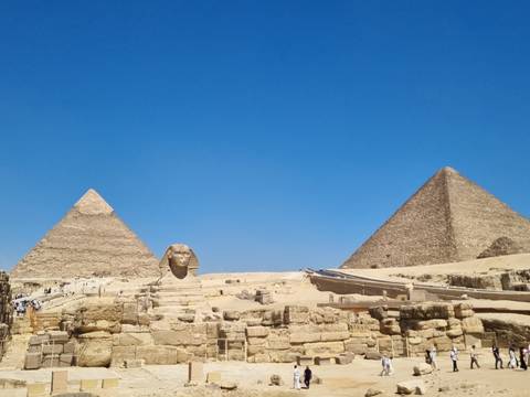 The Great Pyramids and the Sphinx rise majestically from the golden desert under a clear blue sky.