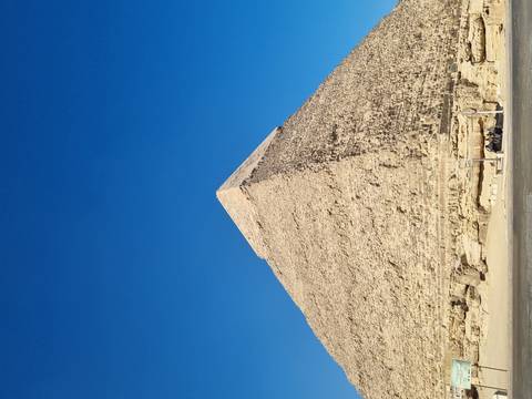 A single limestone pyramid stands sharply against a vivid blue sky.