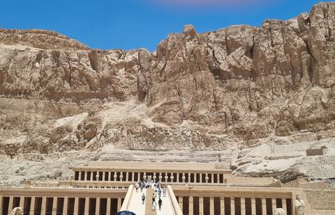 The Temple of Hatshepsut sits beneath towering limestone cliffs in the blazing desert sun.