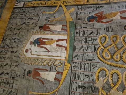 Colorful hieroglyphic wall art depicts Egyptian gods and symbols inside a tomb.