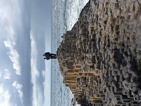 People stand atop the interlocking basalt columns of the Giant's Causeway as waves crash below.