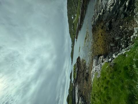 A rocky, sea-weed fringed inlet under a brooding cloudy sky in the Scottish Highlands.