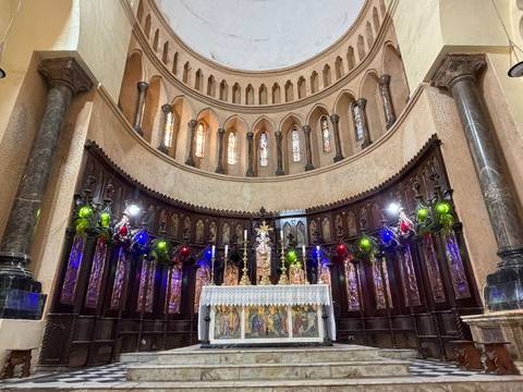 Ornate church altar with colorful lights and gothic arches, captured from central aisle viewpoint.