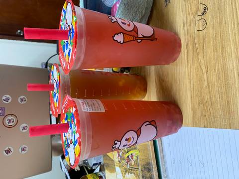 Three tall cups of colourful fruit tea with playful snowman graphics on an office desk.