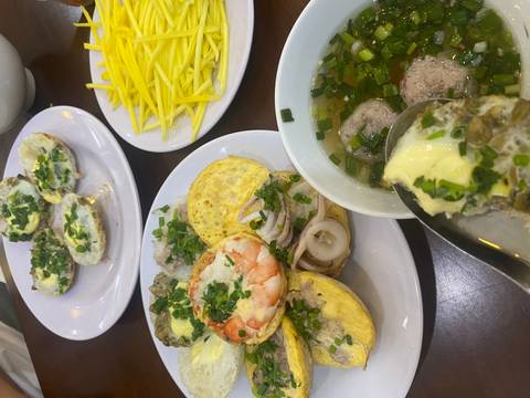 Plates of sizzling Vietnamese mini pancakes topped with shrimp, squid and herbs accompanied by soup and mango.