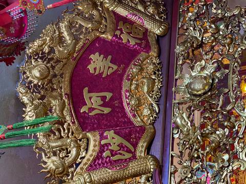 Close-up of ornate golden temple carving with red backdrop and intricate dragon motifs.