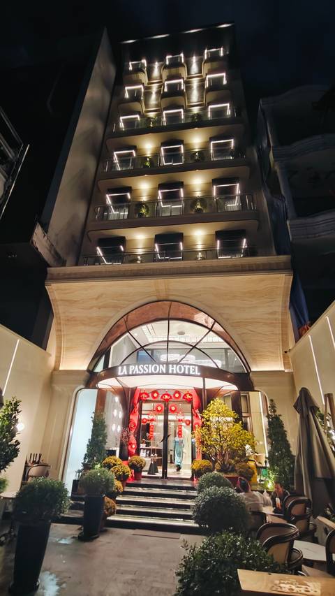 Night view looking up at the warmly lit entrance arch of La Passion Hotel.