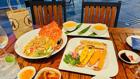 Seafood feast featuring crab fried rice and crab meat dishes served on wooden table.