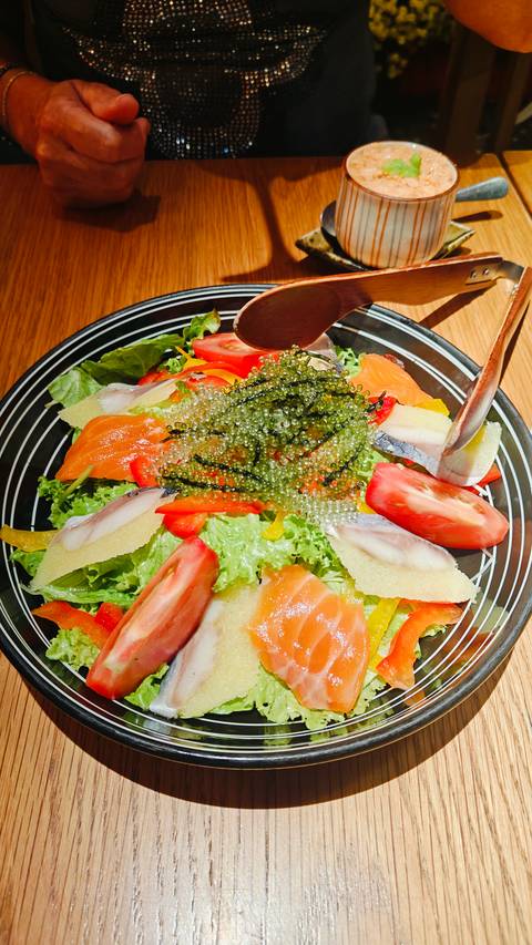 Colorful salad bowl topped with sea grapes, salmon slices, tomatoes and fresh greens.