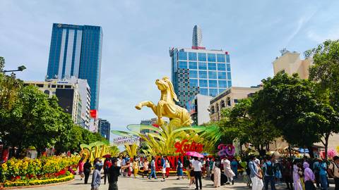 Bustling pedestrian street with towering golden stallion Tet sculpture, modern skyscrapers, and festive crowds.
