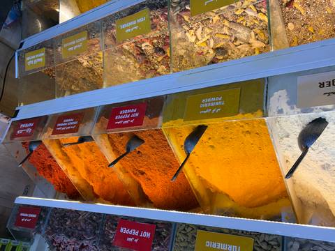 Colorful bins of ground spices such as turmeric and hot pepper on display in a market.