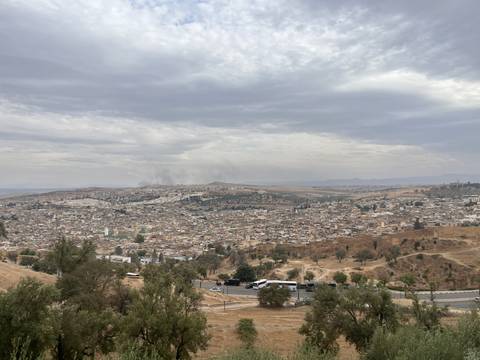 Panoramic overlook of Fes sprawling cityscape under cloudy skies.
