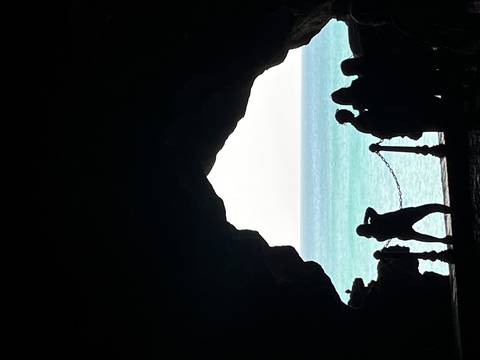 Silhouetted visitors inside Hercules Cave looking out to turquoise Atlantic waters near Tangier.