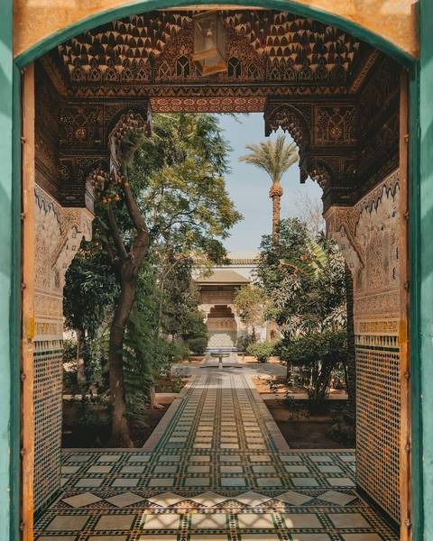 Beautiful riad courtyard in Marrakech featuring ornate tilework, arches, and lush greenery.