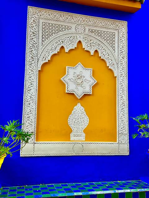 Bright Moroccan architectural detail with yellow wall, ornate white plaster carving and deep cobalt background