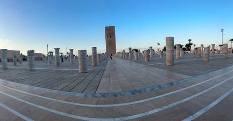 Panoramic view of Hassan Tower plaza in Rabat with lone visitor among stone columns at dusk