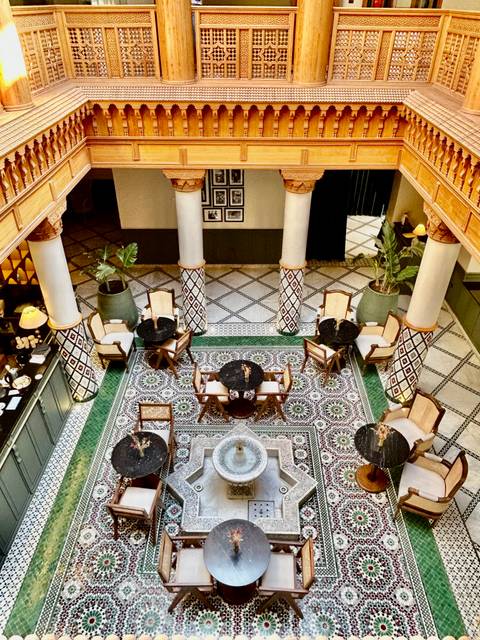 Top-down view of stylish riad lounge with patterned mosaic floor, fountain and elegant furniture