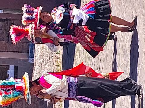 Traditional Peruvian dancers in bright costumes and headdresses performing outdoors, partial view