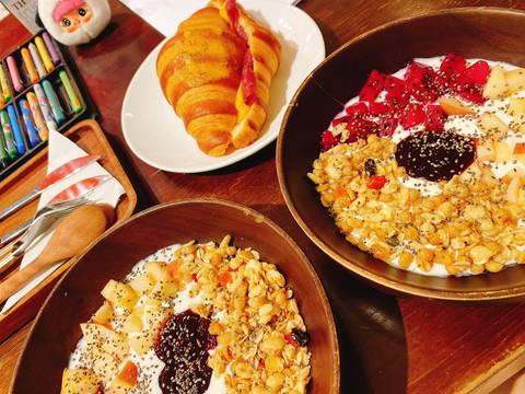 Colorful breakfast spread with granola fruit bowls and croissant on wooden table