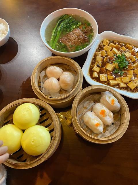 Assorted dim sum baskets with steamed dumplings and custard buns on restaurant table