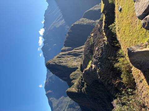 Sunlit morning perspective of Machu Picchu terraces and Huayna Picchu peak under clear sky
