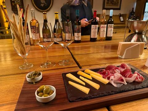 Wine and cheese tasting setup with glasses, olives and charcuterie on a wooden table