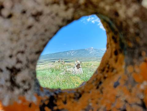Mountain landscape seen through a circular opening in an ancient stone